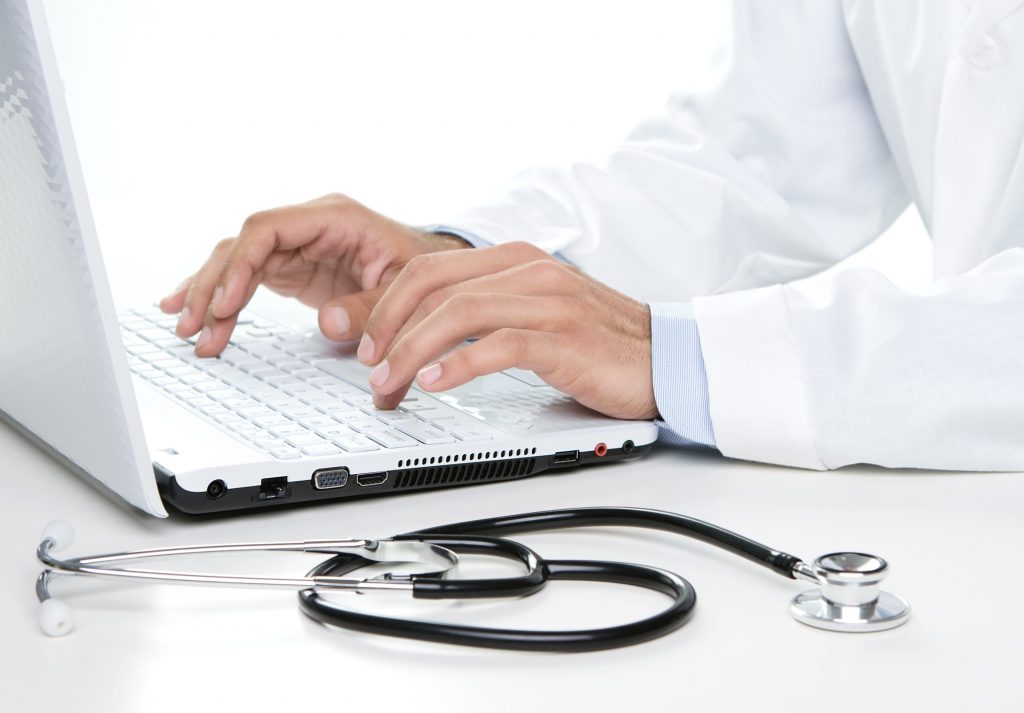 Close up of male doctor working on a laptop electronic medical records